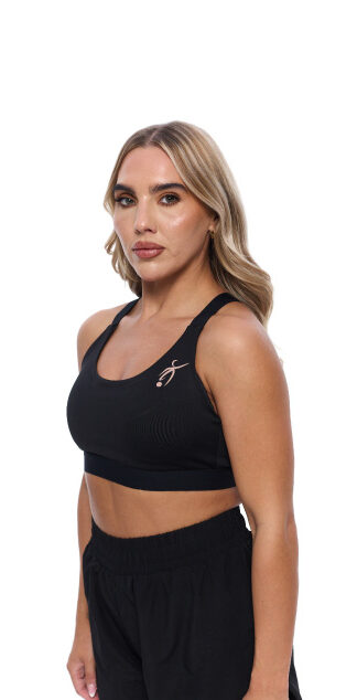 Blonde Female wearing black vest standing in front of a white background