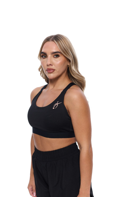 Blonde Female wearing black vest standing in front of a white background