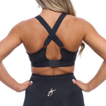 Reverse of Blonde Female wearing black bra standing in front of a white background