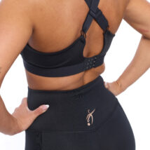 Reverse of Blonde Female wearing black bra standing in front of a white background