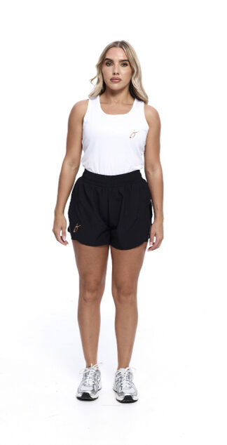Blonde Female wearing White vest black shorts standing in front of a white background