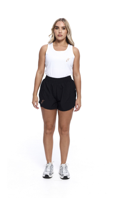 Blonde Female wearing White vest black shorts standing in front of a white background
