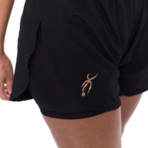 Female wearing black shorts standing in front of a white background