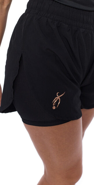 Female wearing black shorts standing in front of a white background