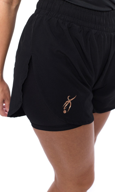 Female wearing black shorts standing in front of a white background