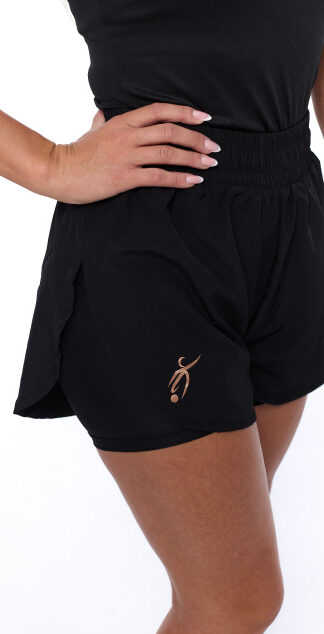 Female wearing black shorts standing in front of a white background