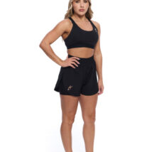 Female wearing black shorts standing in front of a white background