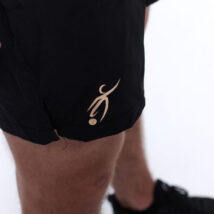 Male wearing black training shorts standing in front of a white background