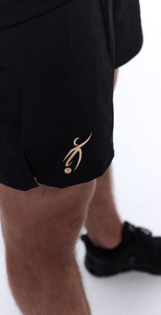 Male wearing black training shorts standing in front of a white background