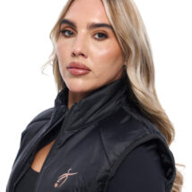 Blonde Female wearing black gilet standing in front of a white background