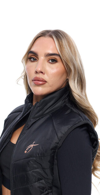 Blonde Female wearing black gilet standing in front of a white background