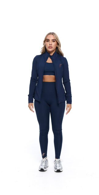 Blonde Female wearing blue tracksuit standing in front of a white background