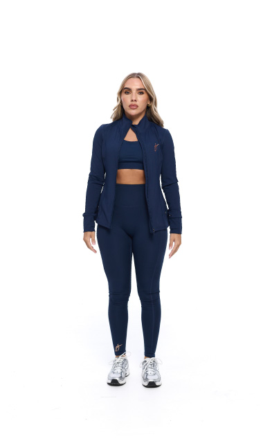 Blonde Female wearing blue tracksuit standing in front of a white background