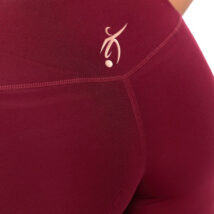 Reverse picture of female wearing red leggings standing in front of a white background