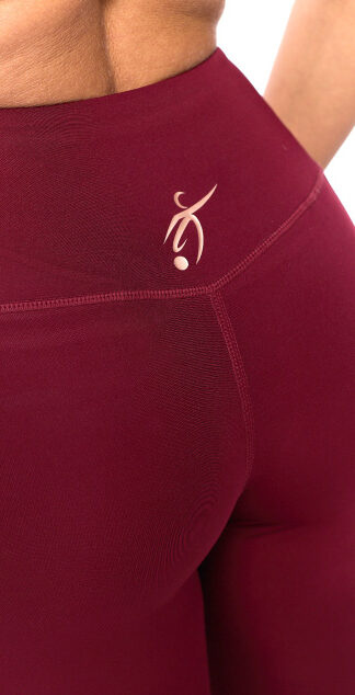 Reverse picture of female wearing red leggings standing in front of a white background