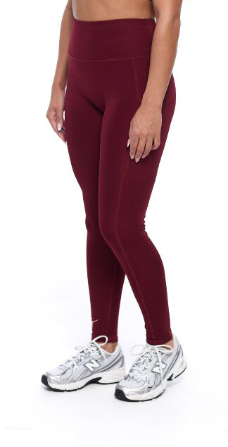 Female wearing Burgandy leggings standing in front of a white background
