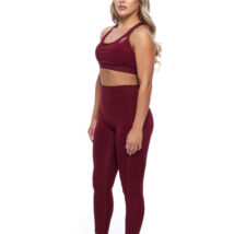 Female wearing Burgandy leggings and matching bra standing in front of a white background