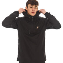Male with black hair fixing his hood wearing black tracksuit bottoms and black rain jacket standing in front of a white wall