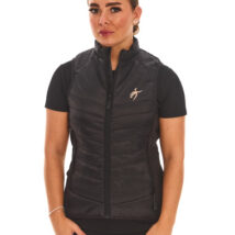 Brown-haired female model wearing a black sports gilet, black leggings, and black trainers, standing against a white wall with hands on hips.