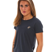 Blonde female wearing blue sports base layers standing in front of white wall