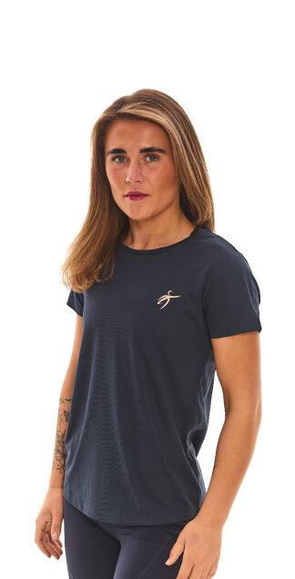 Blonde female wearing blue sports base layers standing in front of white wall